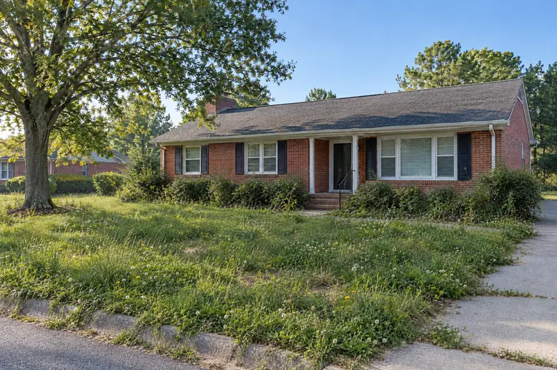 Before: a brick ranch house with an overgrown, weedy front lawn, grass spilling over the sidewalk and shaggy shrubs